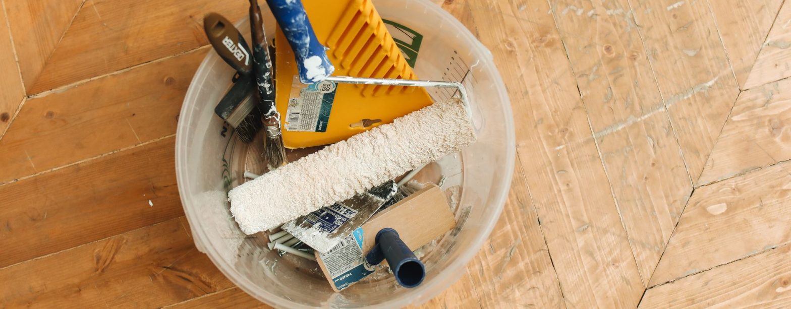 A collection of home renovation tools in a bucket on a wooden floor, ready for a painting project. — "Discover the Best Windo