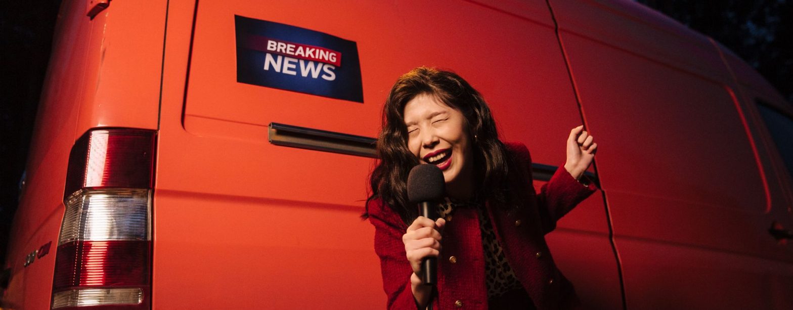 Asian woman reporter energetically broadcasting with a microphone in front of a news van at night. — How a Tobacco Beetle Tra