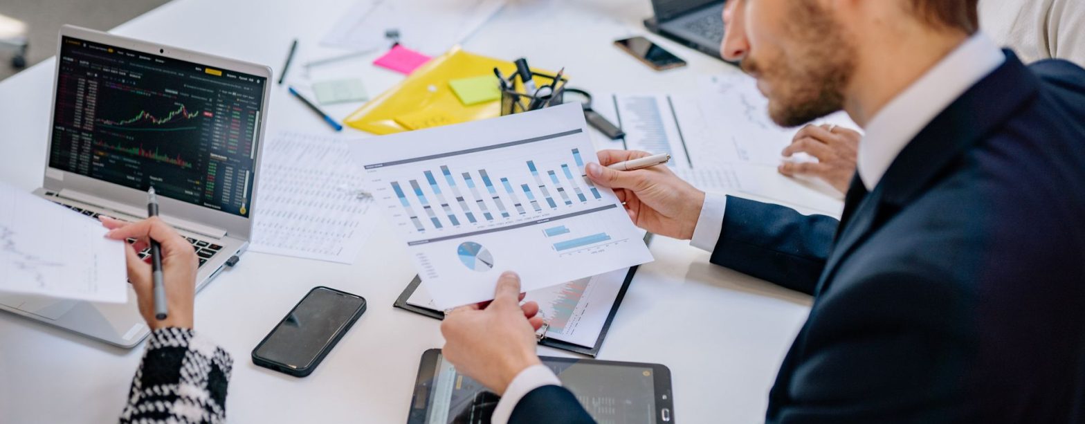 Business team reviewing graphs and data in an office setting. — How Bill Hutchinson Is Shaping the Future of Dallas Neighborh