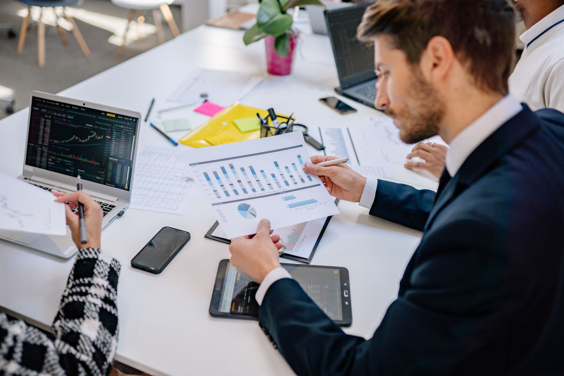 Business team reviewing graphs and data in an office setting. — How Bill Hutchinson Is Shaping the Future of Dallas Neighborh