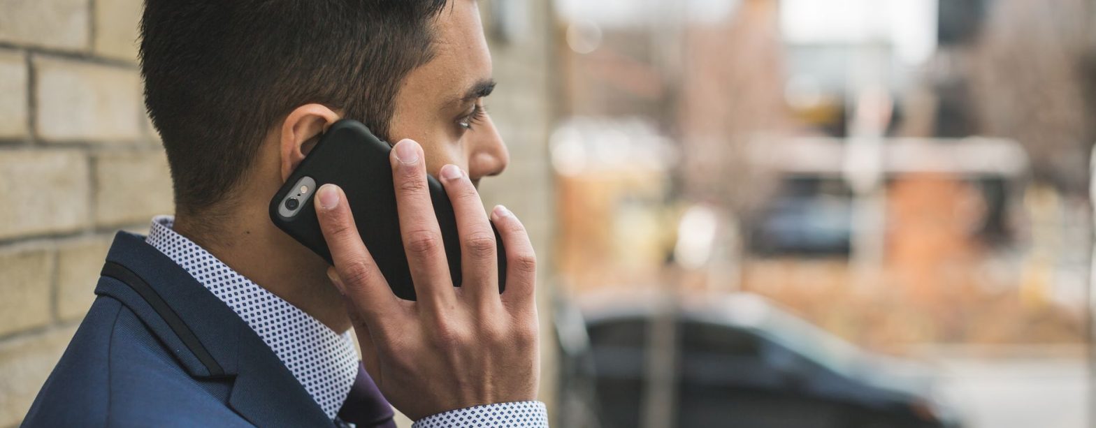 Professional man in suit making a phone call outside in city setting. — How Lessors of Real Estate Provide Housing and Commer
