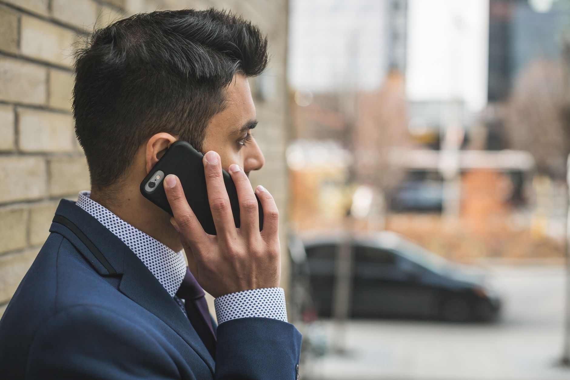 Professional man in suit making a phone call outside in city setting. — How Lessors of Real Estate Provide Housing and Commer