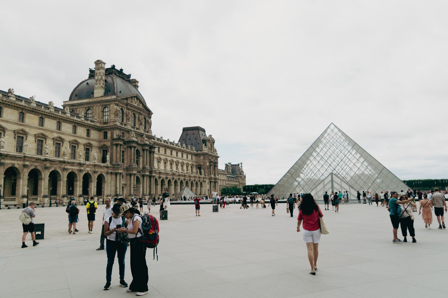 Crowds gather around the iconic Louvre and Pyramid in Paris, showcasing French architecture and culture. — Keep Your Pool Cle