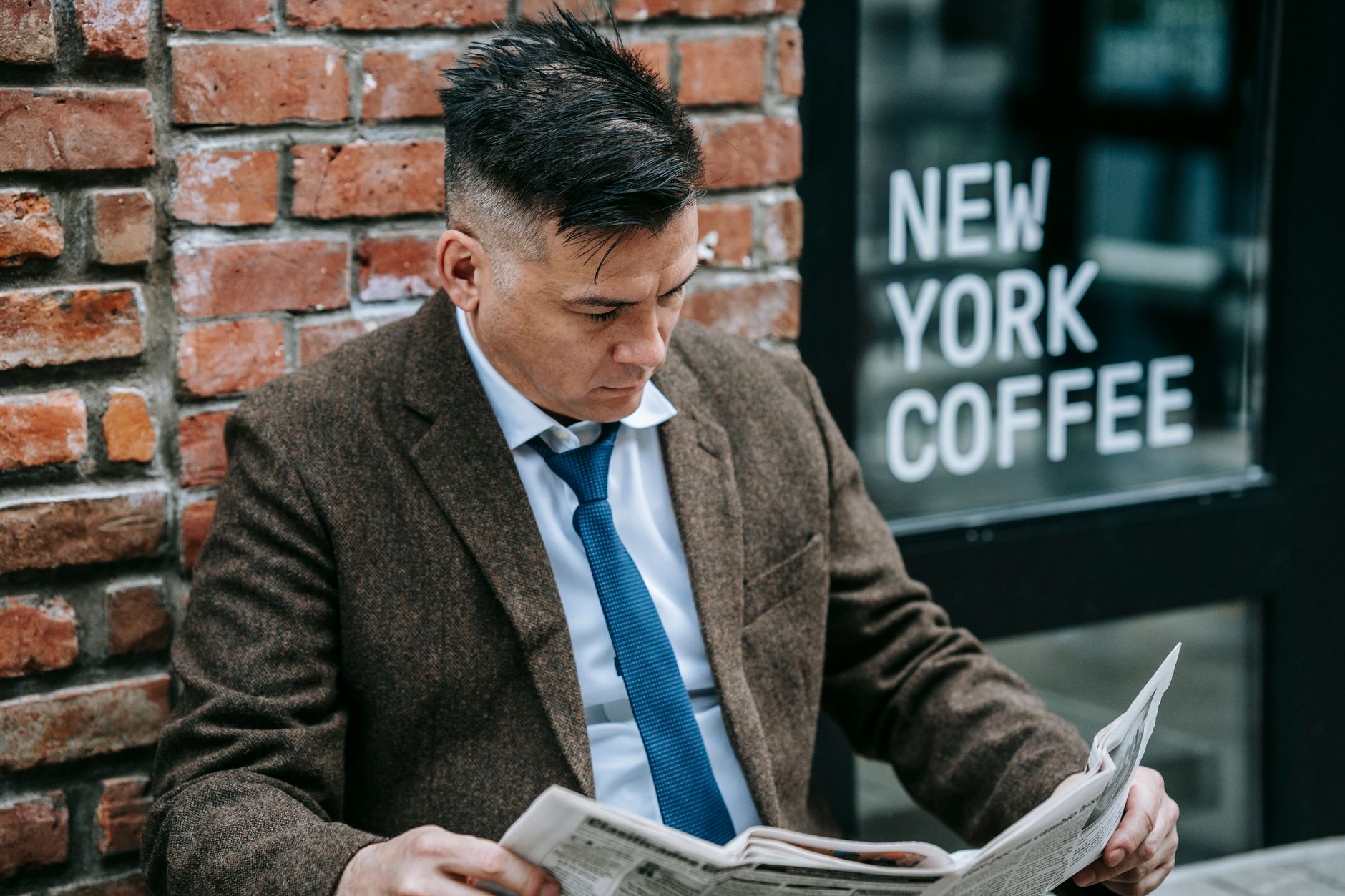 Man in formal attire reading a newspaper outside New York coffee shop. — Nangs Sydney | Professional Nangs Delivery Across Sy