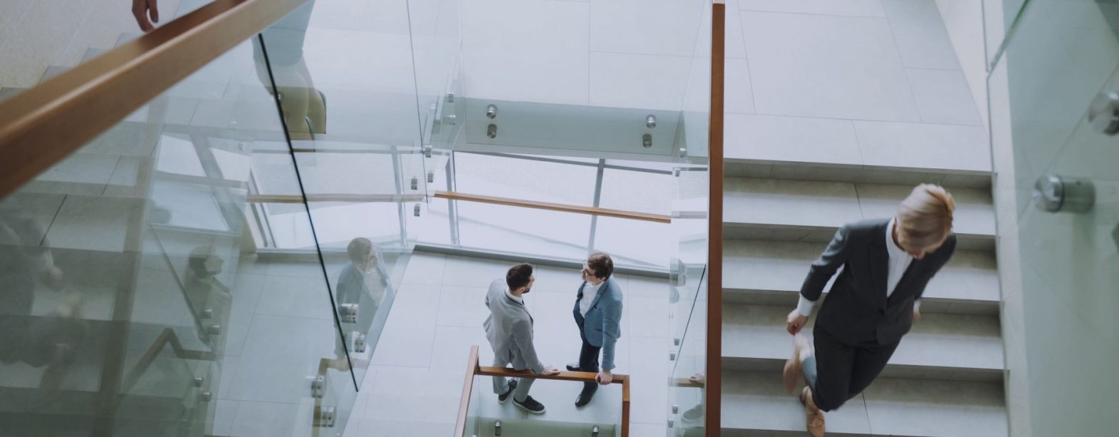 Aerial view of professionals conversing in a glass staircase in a modern office. — Scientific Imaging Evidence for Legal Defe