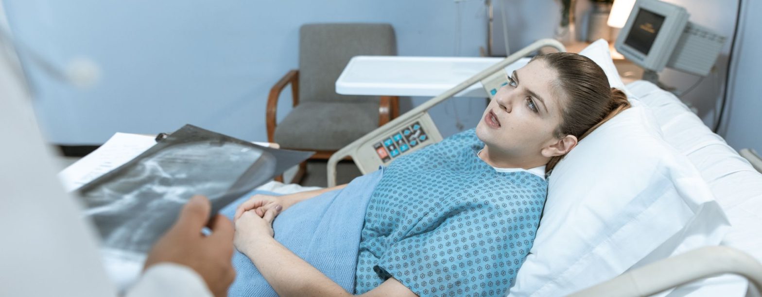 Caucasian woman in hospital bed receiving care from healthcare professional. — The Importance of Ethics in Epidemiology Studi